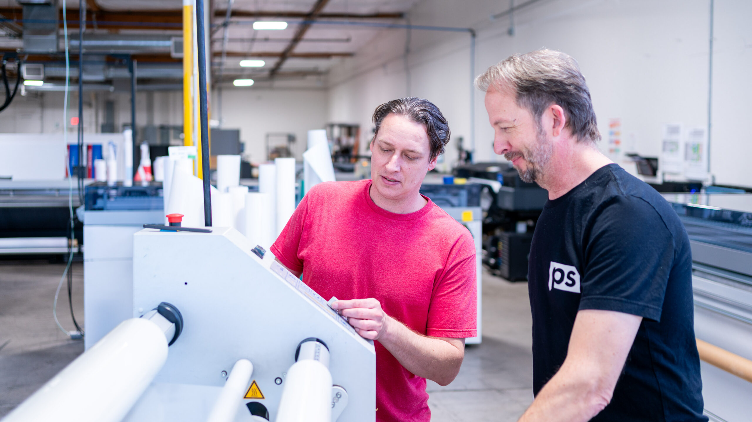 Two employees adjusting controls on a press