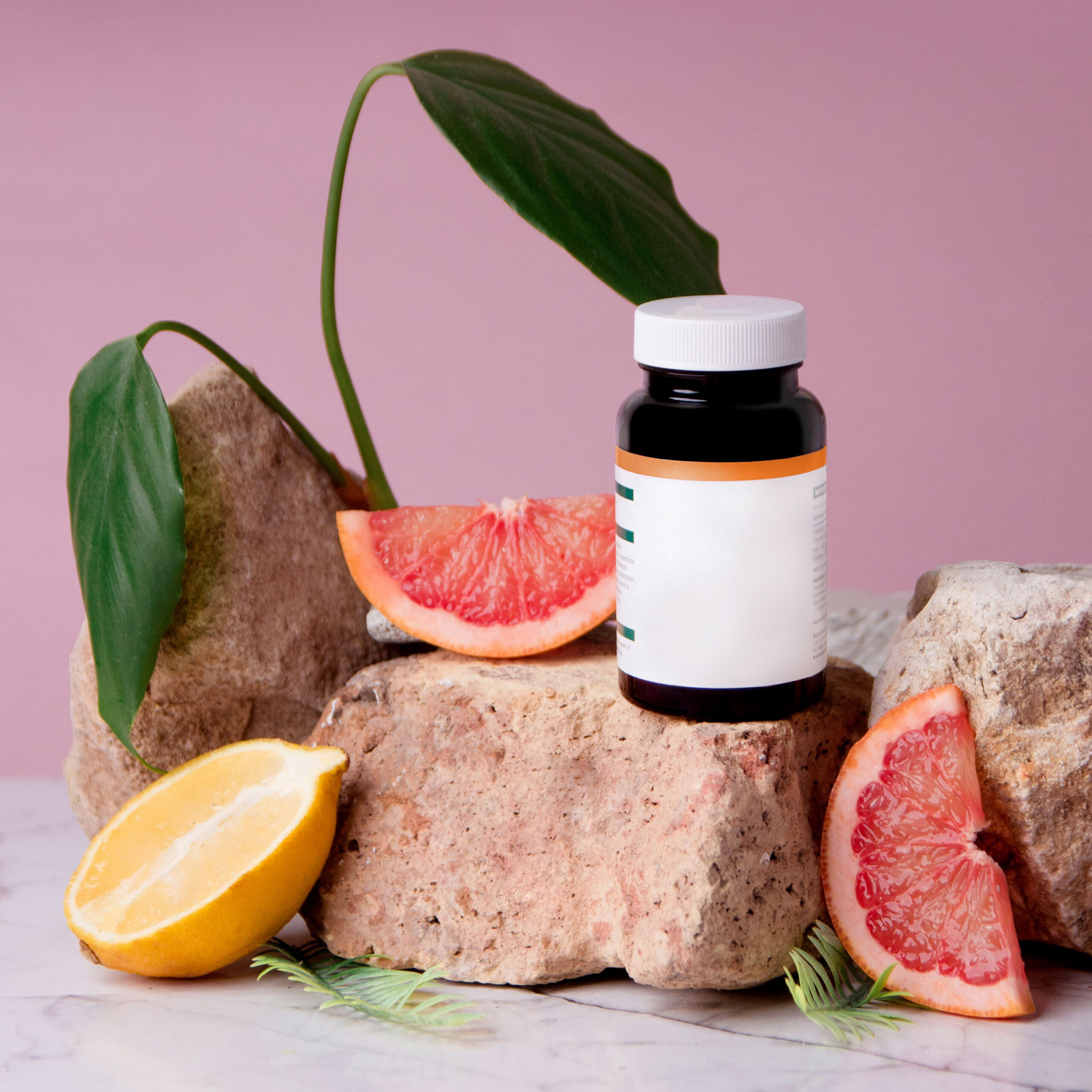 Vitamin jar on rock surrounded by grapefruit and lemons